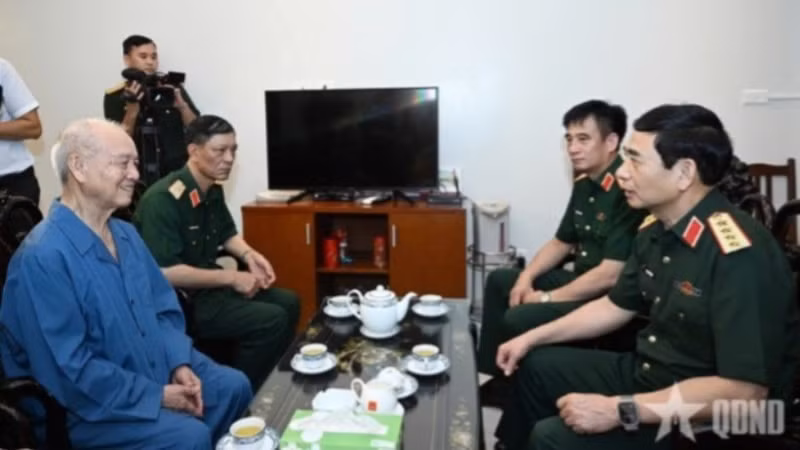 Minister of Defence Phan Van Giang inquires after former Defence Minister Pham Van Tra. (Photo: QDND)