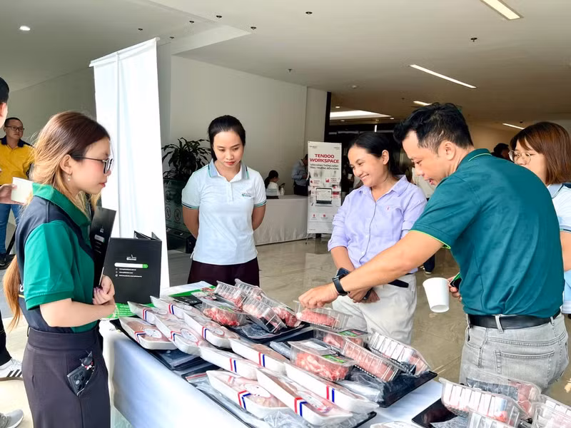 Customers learn about a company’s fresh meat products at a display stall. (Photo: QUANG QUY)