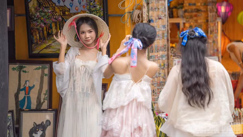 A young woman poses in a traditional conical hat outside an art gallery.