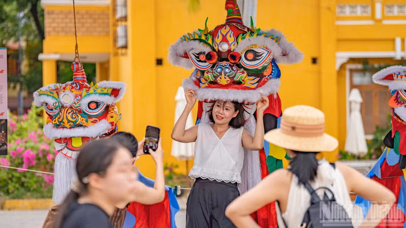 A visitor delights in trying on a colourful lion dance headpiece at an outdoor exhibition space highlighting folk arts.