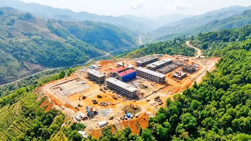 Multi-level boarding schools rise amid the rugged mountain landscape. 