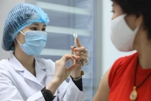 A health worker prepares to administer COVID-19 vaccine to a woman. (Photo: VNA)