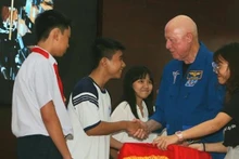 Astronaut Michael Baker and local students at the event. (Photo: VNA)