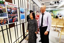 Photographer Nguyen A introduces his works to former Vice President Truong My Hoa at his ‘70 years of Dien Bien Phu Victory - The resounding heroic song’ photo exhibition in Ho Chi Minh City.