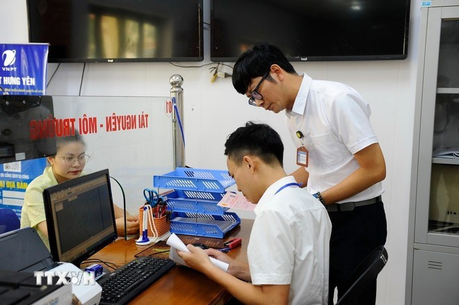 Civil servants at the Public Administration Service Centre of Yen My commune in Hung Yen province handle administrative procedures related to land for a resident. (Photo: VNA)