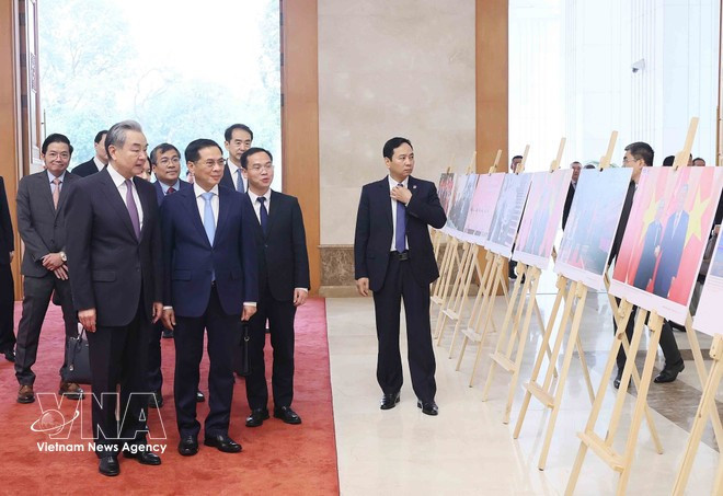 Deputy Prime Minister Bui Thanh Son and Chinese Foreign Minister Wang Yi view a photo exhibition on Viet Nam–China relations held by the Viet Nam News Agency. (Photo: VNA)