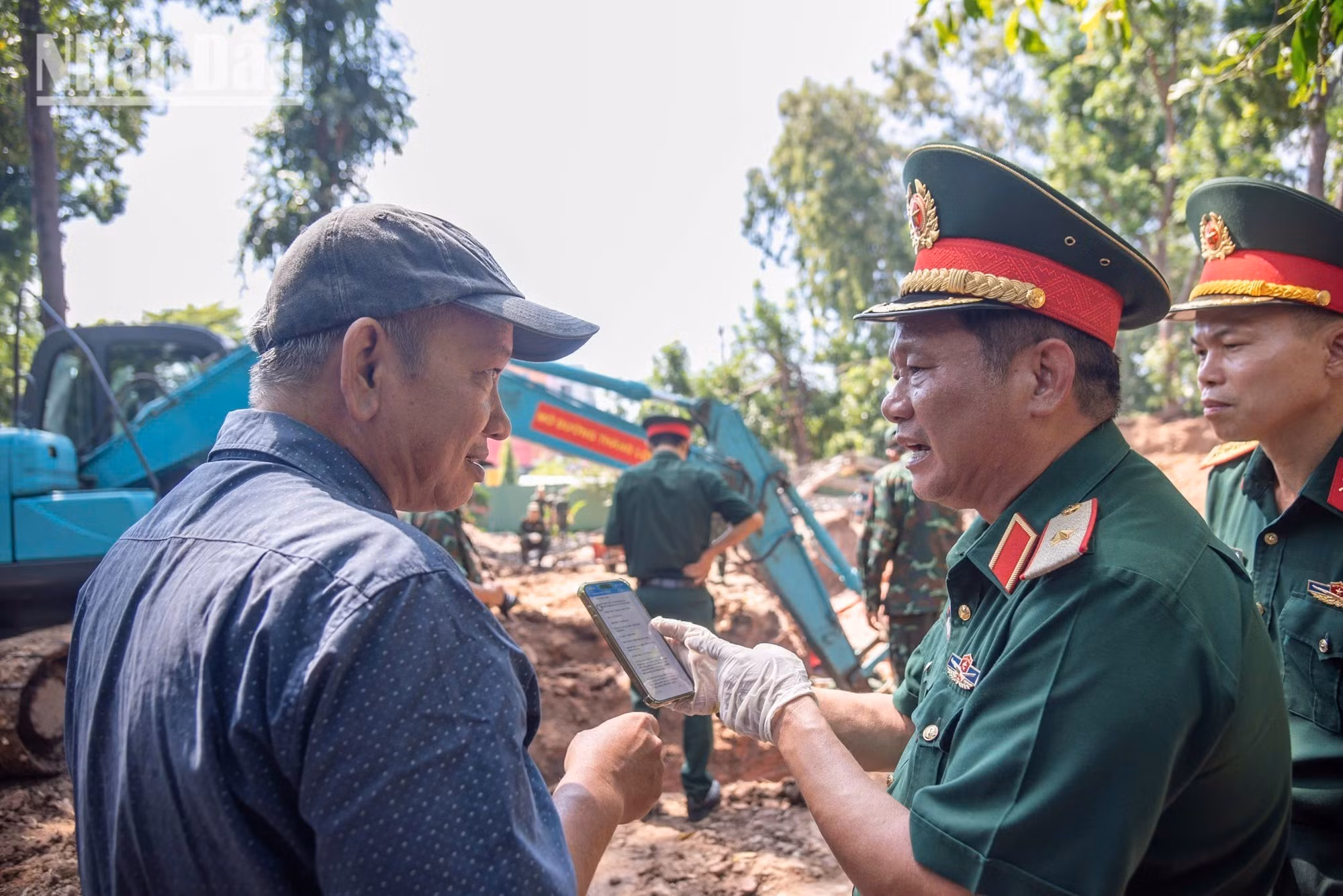 Major General Tran Chi Tam discusses research documents with architect Nguyen Xuan Thang and his team of experts.