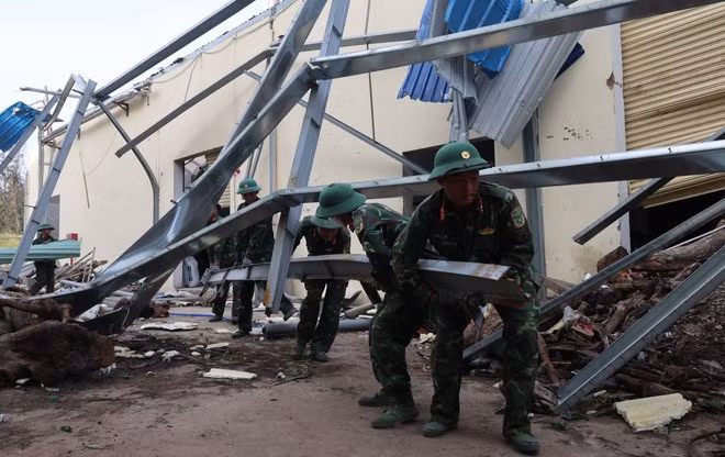 Soldiers of Division 31, Military Region V, help businesses in Nhon Hoi Economic Zone in Gia Lai province clean up factories damaged by storm No. 13 on November 12. (Photo: VNA)