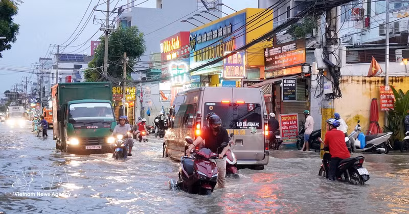 Commuters and vehicles wade through a flooded street in Ho Chi Minh City. (Photo: VNA)