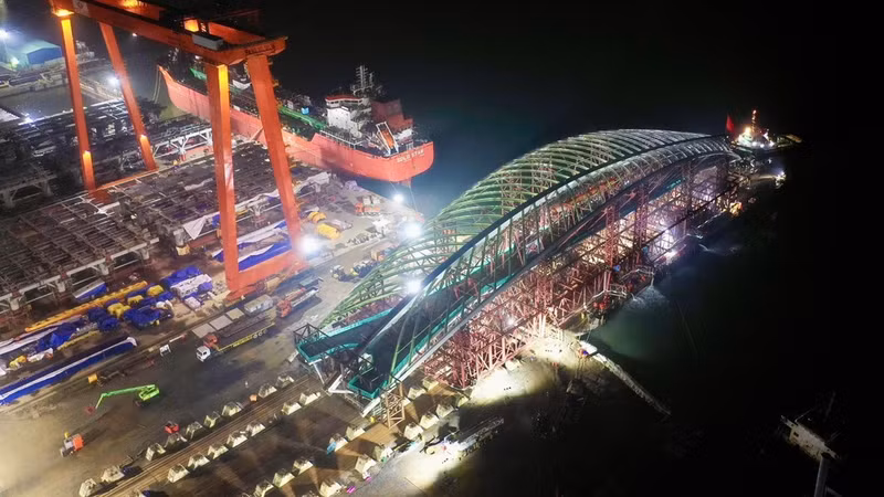 The 3,400-tonne steel arch structure and supporting framework of the pedestrian bridge across the Sai Gon River are successfully loaded onto a specialised barge at Dong Xuyen Port in Vung Tau. (Photo: VO LE)