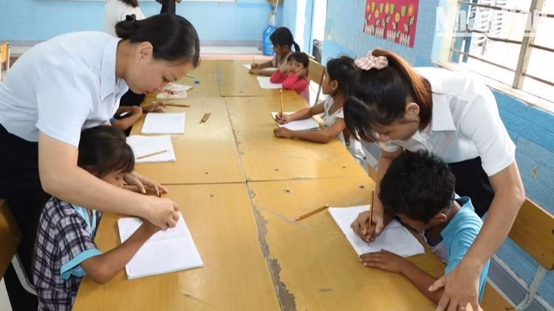 Teachers at Suoi Hai school site, Cam Phuoc Dong 1 Primary School, Ba Ngoi Ward, Khanh Hoa Province, help Raglai ethnic minority pupils practise handwriting during summer classes. (Photo: NGUYEN TRUNG)