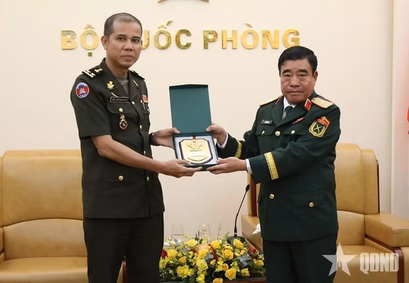 Major General Nguyen Ba Luc (R) presents a gift to Lieutenant General Nim Balene. (Photo: qdnd.vn)