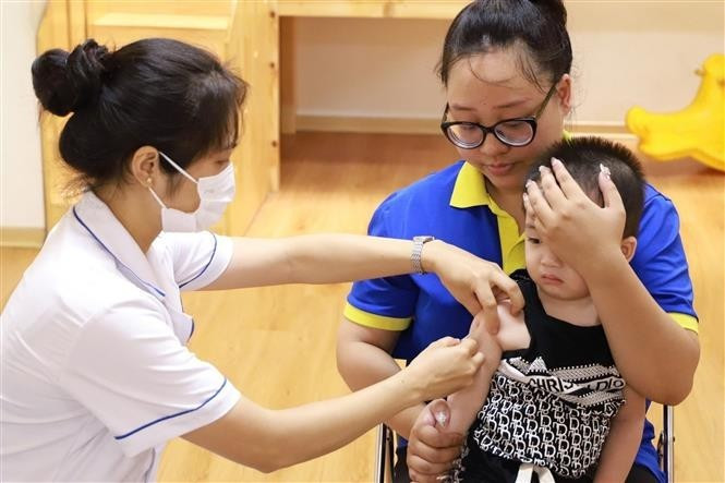 A healthcare worker administers a measles vaccine to a child at a vaccination site in Ha Noi. (Photo: VNA)