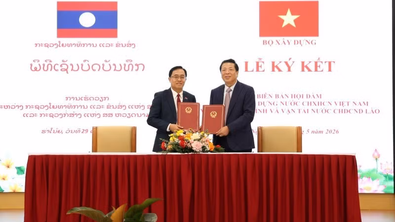 Minister Tran Hong Minh and Minister Leklay Sivilay sign the minutes of the meeting between Viet Nam's Ministry of Construction and Laos' Ministry of Public Works and Transport. (Photo: Ministry of Construction Portal)