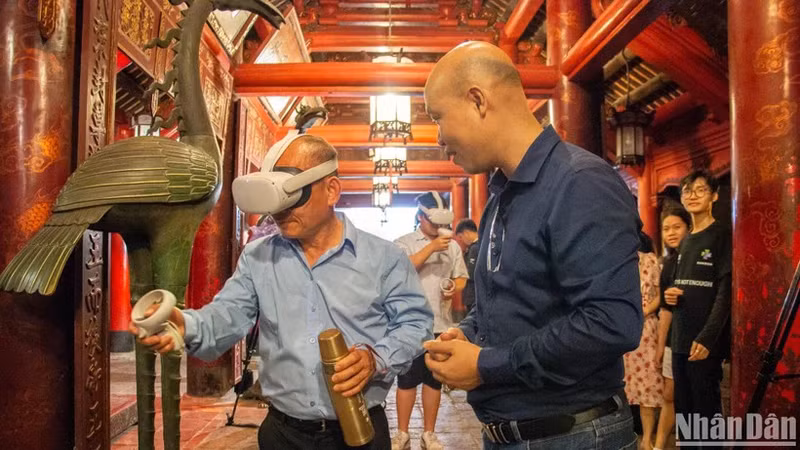 Visitors experience calligraphy writing using virtual reality technology at the Van Mieu - Quoc Tu Giam (The Temple of Literature). (Photo: HA NAM)