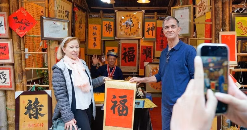 International visitors experience the traditional new year calligraphy activity (Photo: VNA)