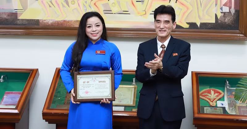 Ambassador Ri Sung Guk presents the gold cup and certificate of merit to Meritorious Artist To Nga. (Photo courtesy of the artist)