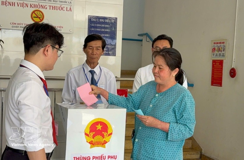 A voter under treatment at the Ho Chi Minh City Hospital of Dermato-Venereology drops her ballot into a mobile ballot box on March 15. (Photo: VNA)