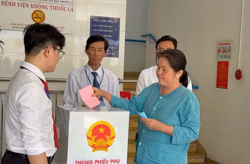 A voter under treatment at the Ho Chi Minh City Hospital of Dermato-Venereology drops her ballot into a mobile ballot box on March 15. (Photo: VNA)