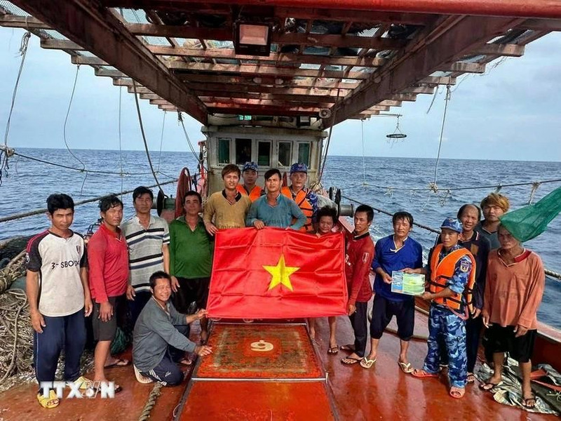 Ho Chi Minh City's maritime law enforcement staff distribute a national flag and raise anti-IUU awareness among fishermen (Photo: VNA)