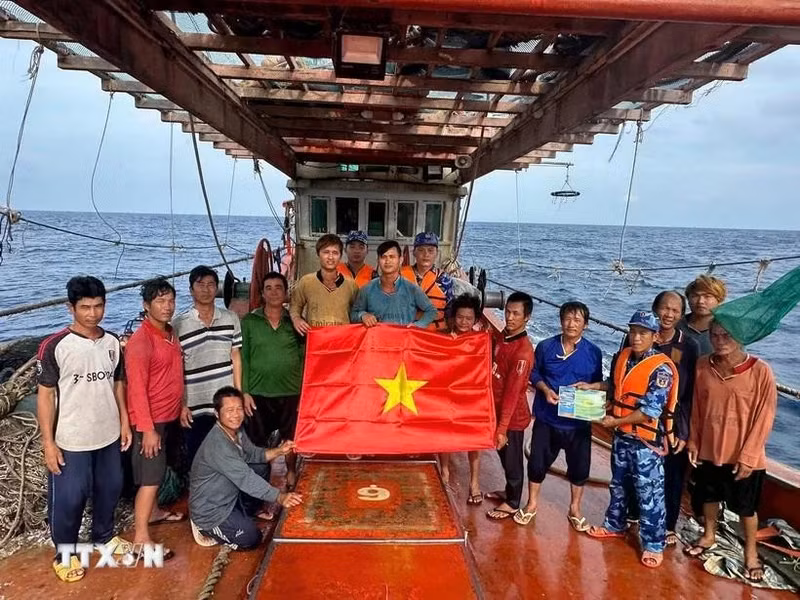 Ho Chi Minh City's maritime law enforcement staff distribute a national flag and raise anti-IUU awareness among fishermen (Photo: VNA)