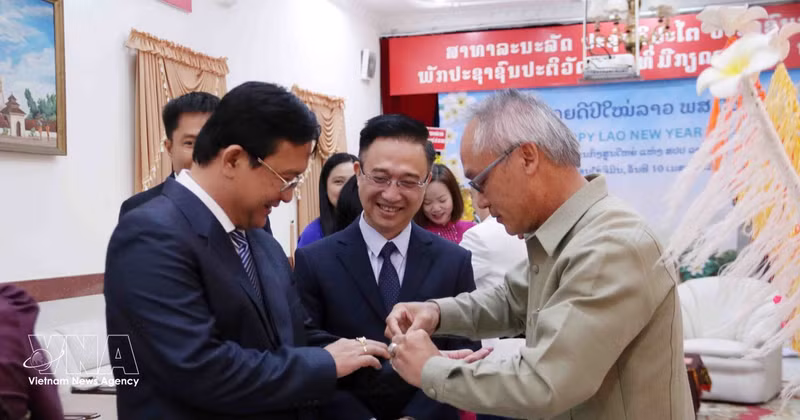 Phonesy Bounmixay (right), Lao Consul General in Ho Chi Minh City, performs the traditional baci string-tying ceremony to offer New Year blessings to a member of the Ho Chi Minh City delegation on April 10, 2026. (Photo: VNA)