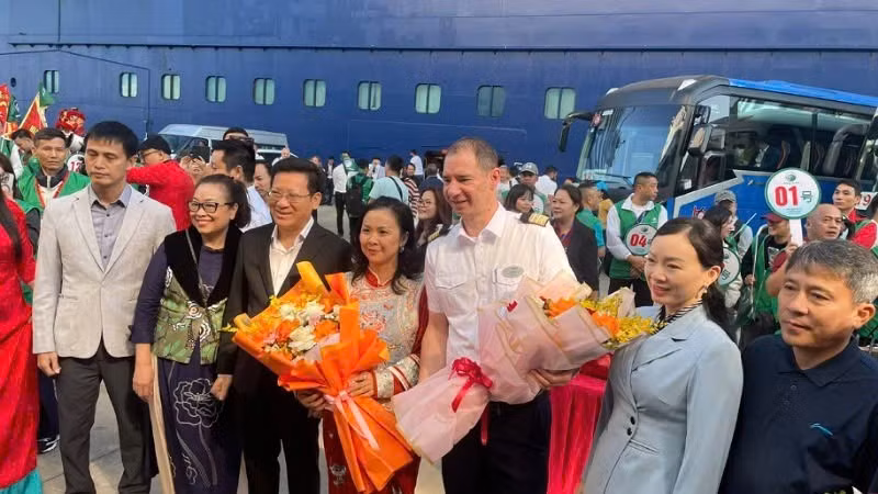 A representative of the Department of Culture, Sports and Tourism of Quang Ninh presents flowers to tourists arriving from Beihai (China).