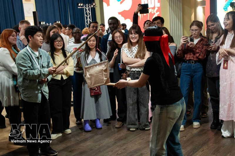 Young participants from India, Indonesia and Russia learn about the traditional pot-breaking game. (Photo: VNA)