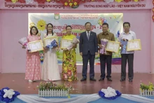 Vietnamese Ambassador to Laos Nguyen Minh Tam presents certificates of merit to the Vietnamese community in Vientiane and leaders of the Nguyen Du Lao-Vietnamese bilingual school for their contributions to preserving Vietnamese culture. (Photo: VNA)