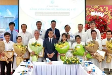 Deputy Minister of Health Tran Van Thuan presents flowers and certificates of merit to the team who performed the fetal intervention for the Singaporean mother. (Photo: HOANG HUNG)