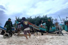 Officers and soldiers of Roon Border Guard Station (Quang Tri Province) help locals pull and move fishing boats ashore.