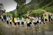 The wedding procession crosses the stream. (Photo: Vu Linh)
