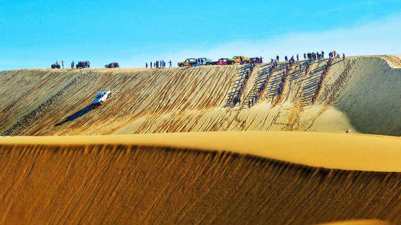 Tourists tackle dunes on off-road vehicles. Tourists tackle dunes on off-road vehicles.