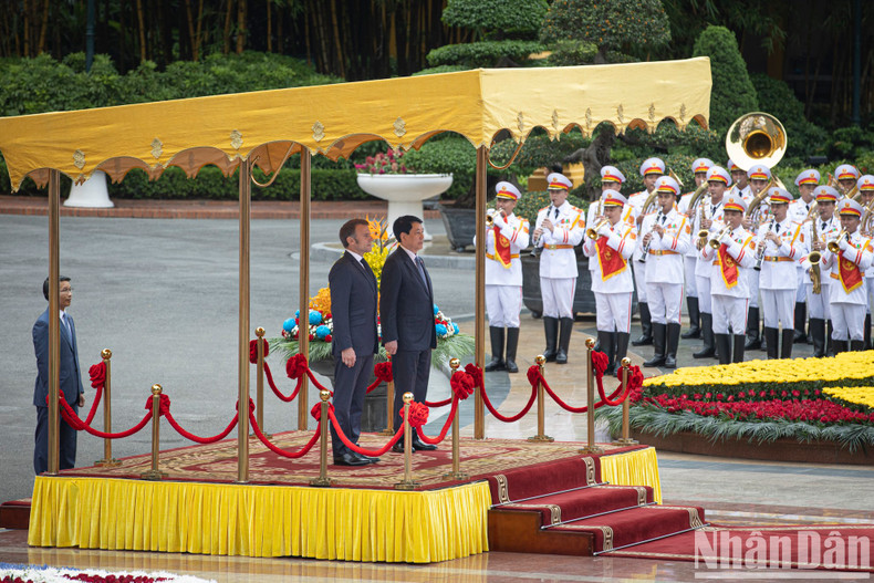 State President Luong Cuong and President Emmanuel Macron stand on the ceremonial platform as the military band plays the national anthems of both countries.