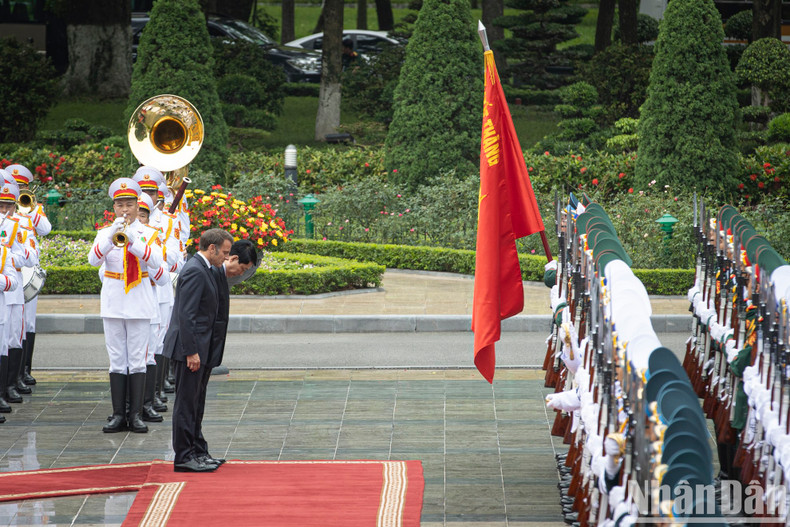 State President Luong Cuong and President Emmanuel Macron bow before the Victory Flag of the Viet Nam People’s Army.
