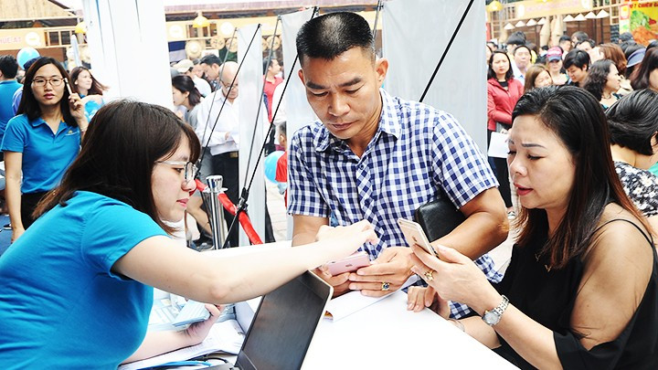 A tourism company instructing customers on how to use a digital service app. (Photo: HAI NAM)