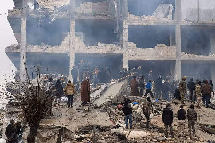 People gather as rescuers search for survivors under the rubble, following an earthquake, in rebel-held town of Jandaris, Syria. (Credit: Reuters Photo)
