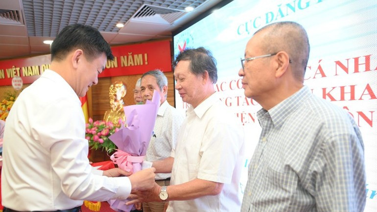 Nguyen Chien Thang, Director of the Viet Nam Register, presents flowers to former leaders of the agency in recognition of their substantial contributions to the field of vehicle registration. (Photo: THE DAI)