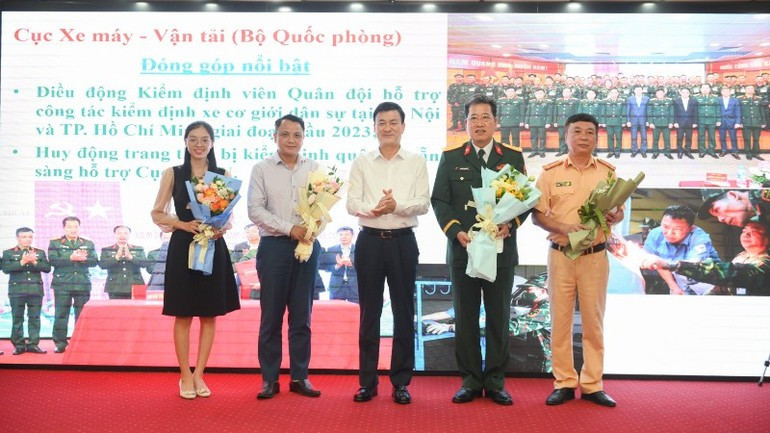 Nguyen Chien Thang, Director of the Viet Nam Register, presents flowers to representatives from the Traffic Police Department (Ministry of Public Security) and the Department of Military Transport and Motor Vehicles (Ministry of National Defence). (Photo: THE DAI)