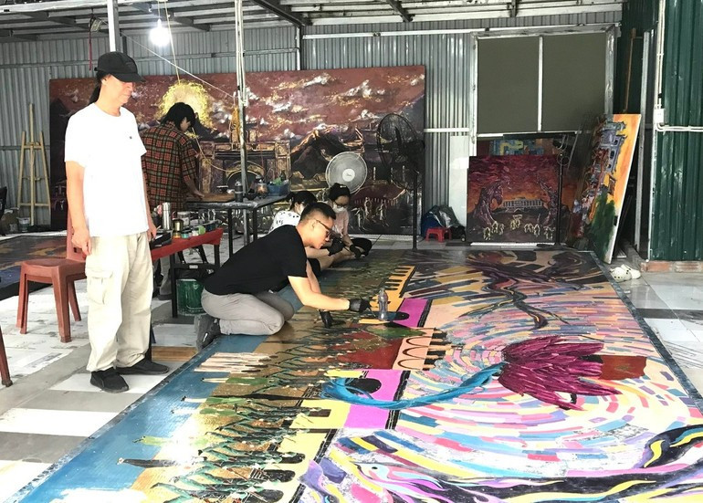 Painter Chu Nhat Quang works on the painting, with input from his father, Meritorious Artist Chu Luong. Painter Chu Nhat Quang works on the painting, with input from his father, Meritorious Artist Chu Luong.