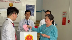 A voter under treatment at the Ho Chi Minh City Hospital of Dermato-Venereology drops her ballot into a mobile ballot box on March 15. (Photo: VNA)