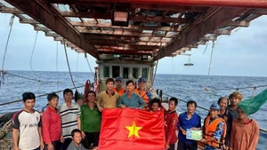 Ho Chi Minh City's maritime law enforcement staff distribute a national flag and raise anti-IUU awareness among fishermen (Photo: VNA)