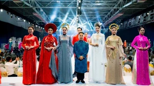 Designer Nguyen Viet Hung and models present a collection of traditional ao dai for Vietnamese women, created using Thai Tuan fabric.