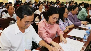 Delegates review brief biographical profiles of candidates for the 16th National Assembly at a consultative conference. (Photo: VNA)