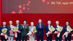 Party General Secretary To Lam (fourth, right) and Minister of Public Security General Luong Tam Quang (fourth, left) present flowers and gifts to former public security officers. (Photo: VNA)