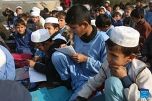 Students attend an outdoor class at a makeshift roadside school without proper shelters beside a highway junction in Nangarhar province, eastern Afghanistan, Dec. 16, 2025. (Photo: Xinhua)