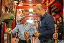 Visitors experience calligraphy writing using virtual reality technology at the Van Mieu - Quoc Tu Giam (The Temple of Literature). (Photo: HA NAM)
