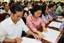 Delegates review brief biographical profiles of candidates for the 16th National Assembly at a consultative conference. (Photo: VNA)
