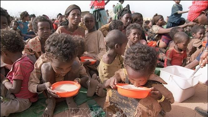 Two malnourished children drink milk from their plastic bowls at the Kebribeyah refugee camp in eastern Ethiopia (Photo: AFP/VNA)