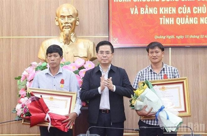 Chairman of the Quang Ngai provincial People's Committee Nguyen Hoang Giang (centre) presents the State President's Bravery Order to two citizens of Ly Son special zone on December 15. (Photo: NDO)
